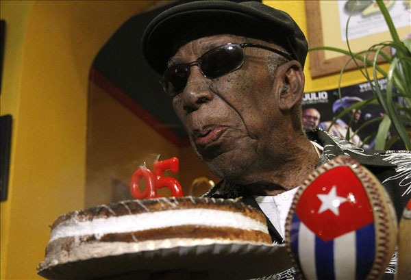 El cantante de la Vieja Trova Santiaguera, Reinaldo Creagh, sopla las velas de su 95 cumpleaños, que hoy ha celebrado tomando mojitos con varios periodistas en un bar del madrileño barrio de Lavapiés. © EFE