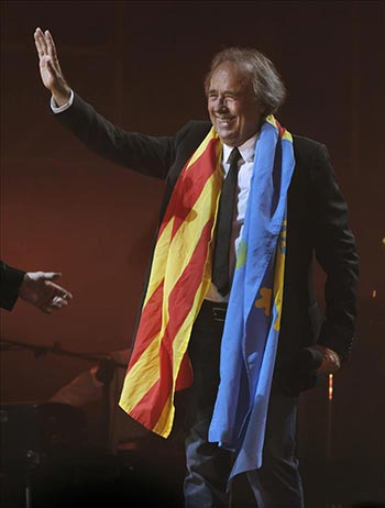 El cantante catalán Joan Manuel Serrat se despide del público envuelto en las banderas catalana y asturiana. © EFE